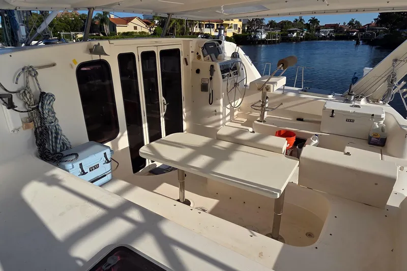 Beshert Yacht Photos Pics 2004 Leopard 47 catamaran cockpit with seating, table, and waterfront view.