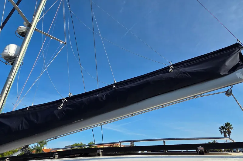Beshert Yacht Photos Pics Sailboat mast and boom of a 2004 Leopard 47 under clear blue sky.