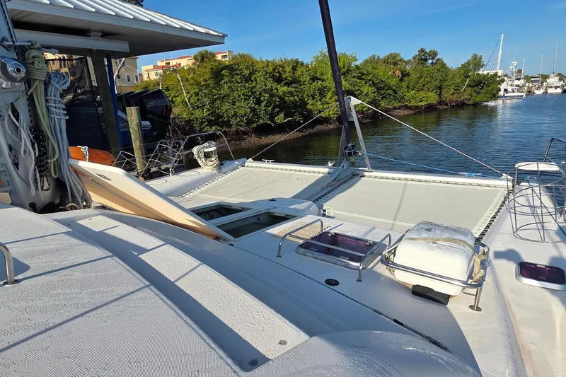 Beshert Yacht Photos Pics 2004 Leopard 47 catamaran docked by lush greenery and calm waters.