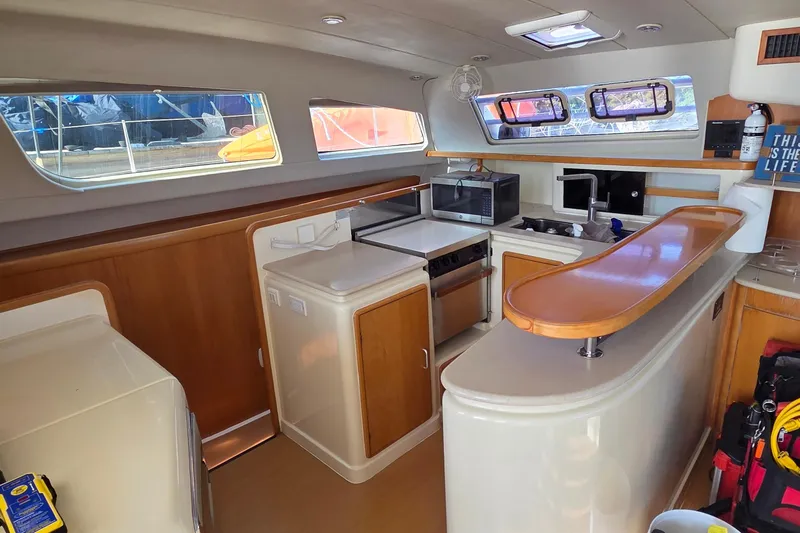 Beshert Yacht Photos Pics Interior of 2004 Leopard 47 catamaran kitchen with modern appliances and wooden accents.