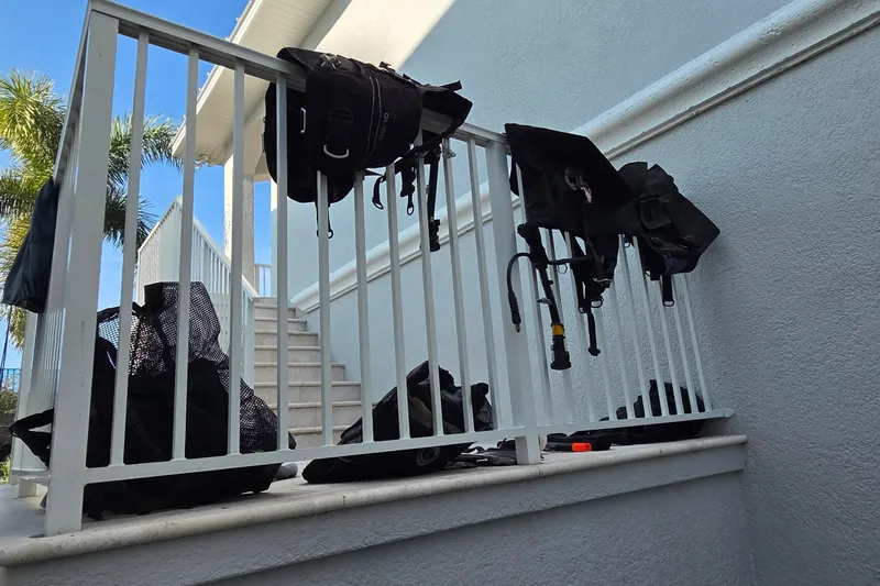 Beshert Yacht Photos Pics Diving gear drying on a white railing, with palm trees and stairs in the background.