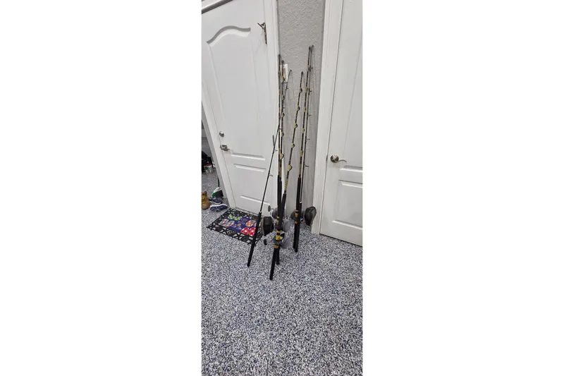 Beshert Yacht Photos Pics Fishing rods leaning against a wall in a carpeted room, near white doors.