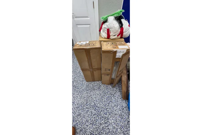 Beshert Yacht Photos Pics Cardboard boxes and bags on speckled floor, near a white door.