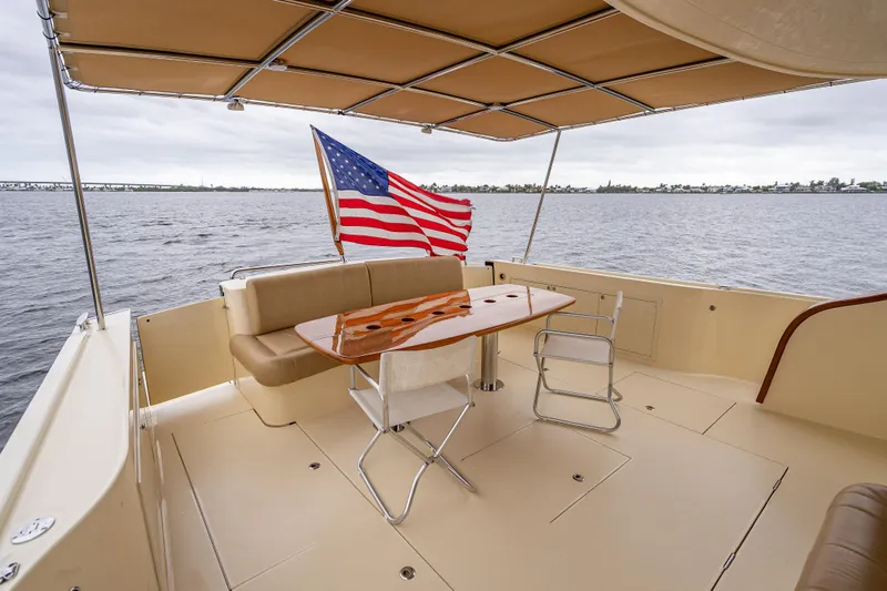 Carole Lyn Yacht Photos Pics 2018 Palm Beach Motor Yachts PB55 deck with seating, table, and American flag.