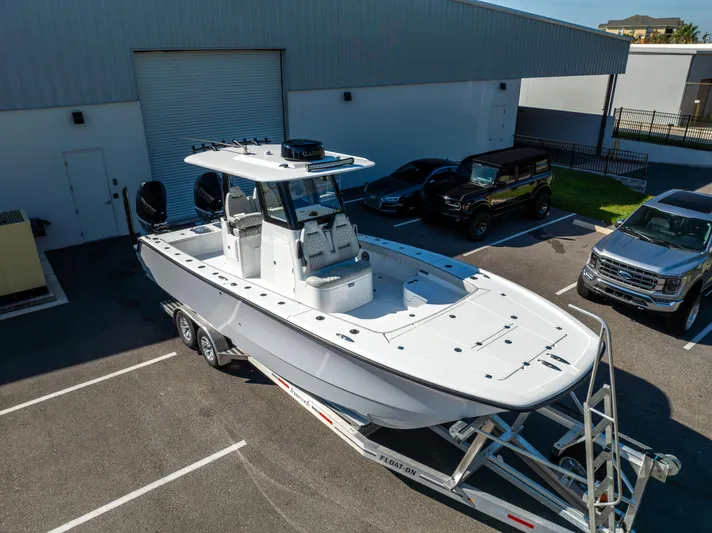  Yacht Photos Pics 2024 Freeman 28 boat on trailer in parking lot, near vehicles and building.