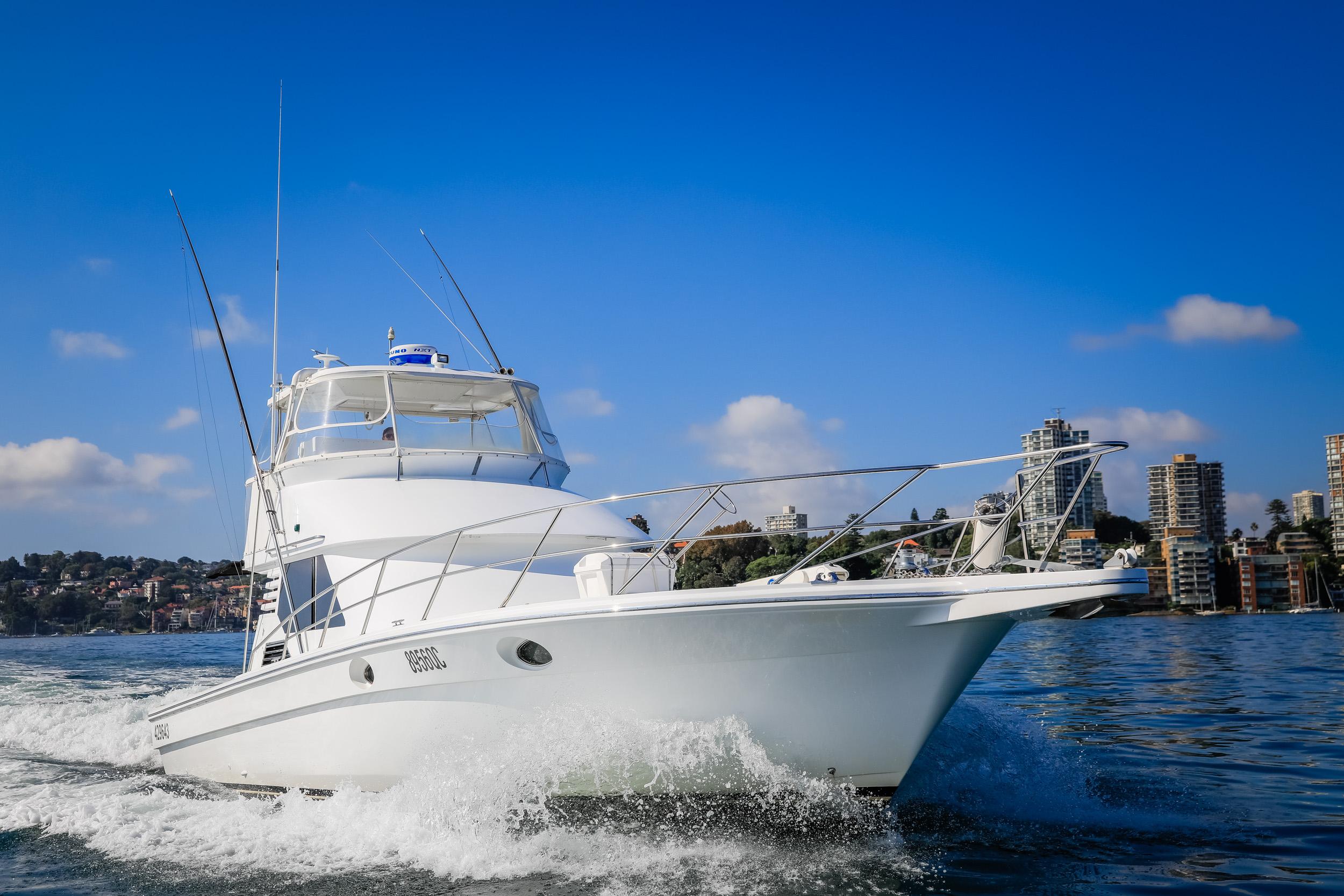 1993 Precision 47 Flybridge yacht cruising on a sunny day with city skyline backdrop.
