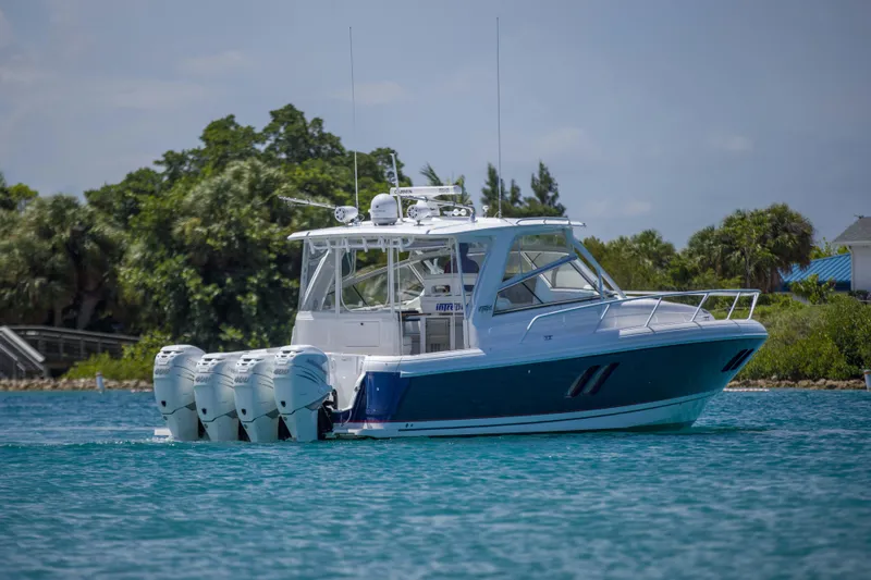 Sunkisser Yacht Photos Pics 2013 Intrepid 475 Sport Yacht cruising on blue water, surrounded by lush greenery.