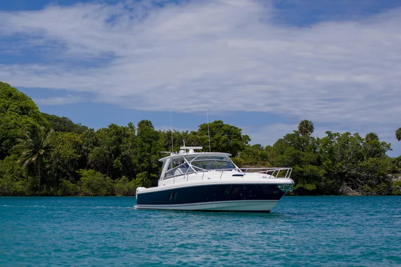 Sunkisser Yacht Photos Pics 2013 Intrepid 475 Sport Yacht on turquoise water near lush green shoreline.