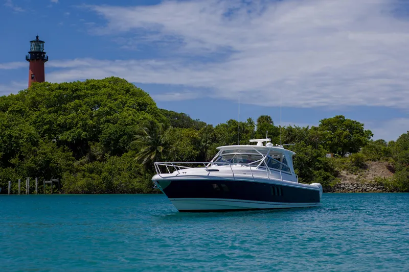 Sunkisser Yacht Photos Pics 2013 Intrepid 475 Sport Yacht on turquoise water near lush greenery and lighthouse.