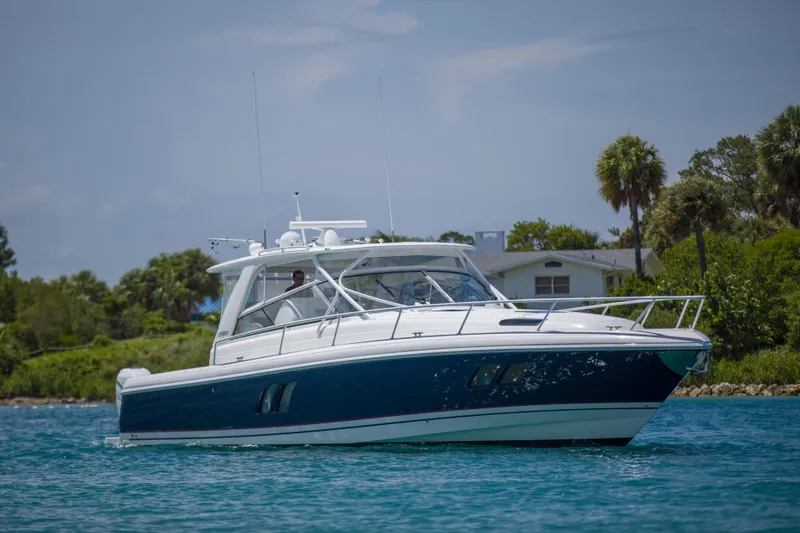 Sunkisser Yacht Photos Pics 2013 Intrepid 475 Sport Yacht cruising on a sunny day near a lush shoreline.