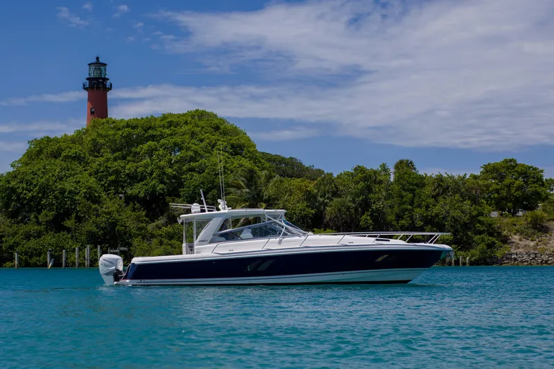 Sunkisser Yacht Photos Pics 2013 Intrepid 475 Sport Yacht cruising near a lush island with a lighthouse.