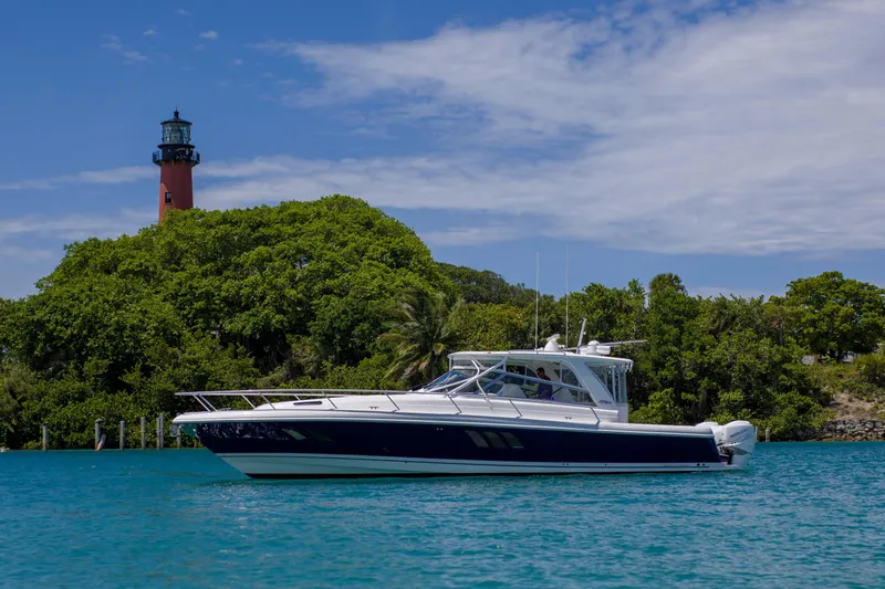 Sunkisser Yacht Photos Pics 2013 Intrepid 475 Sport Yacht cruising near a lighthouse and lush greenery.