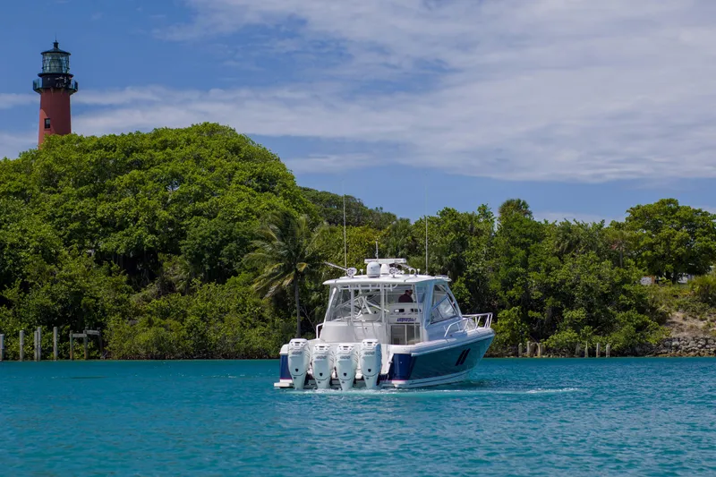Sunkisser Yacht Photos Pics 2013 Intrepid 475 Sport Yacht cruising near a lush island with a lighthouse.