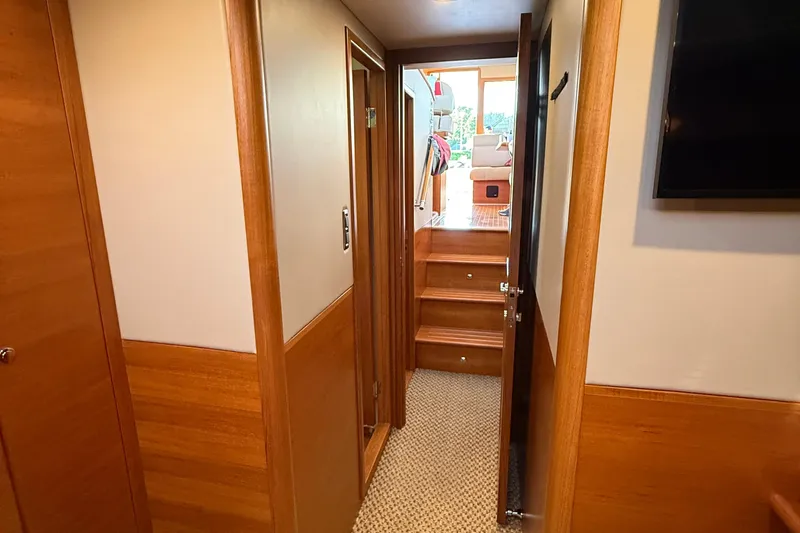  Yacht Photos Pics Interior hallway of 2017 Grand Banks 44 Eastbay SX yacht, featuring wooden finishes and carpeted flooring.