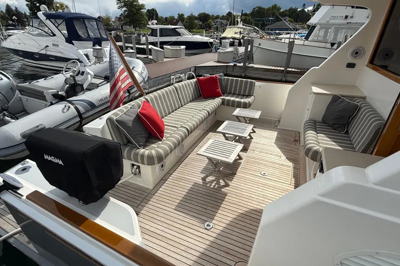  Yacht Photos Pics 2017 Grand Banks 44 Eastbay SX yacht with striped seating and American flag at marina.