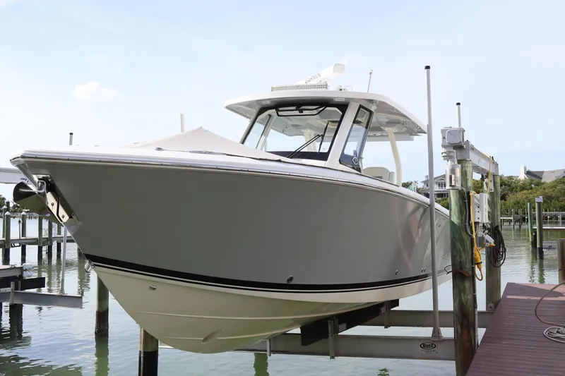  Yacht Photos Pics 2021 Pursuit S 328 Sport boat docked on a lift by the water.