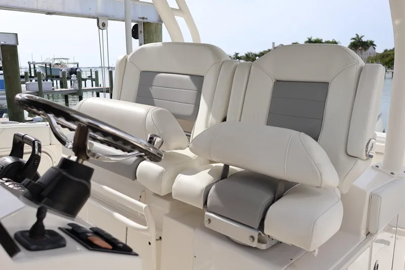  Yacht Photos Pics 2021 Pursuit S 328 Sport boat interior with dual captain's chairs and steering wheel.