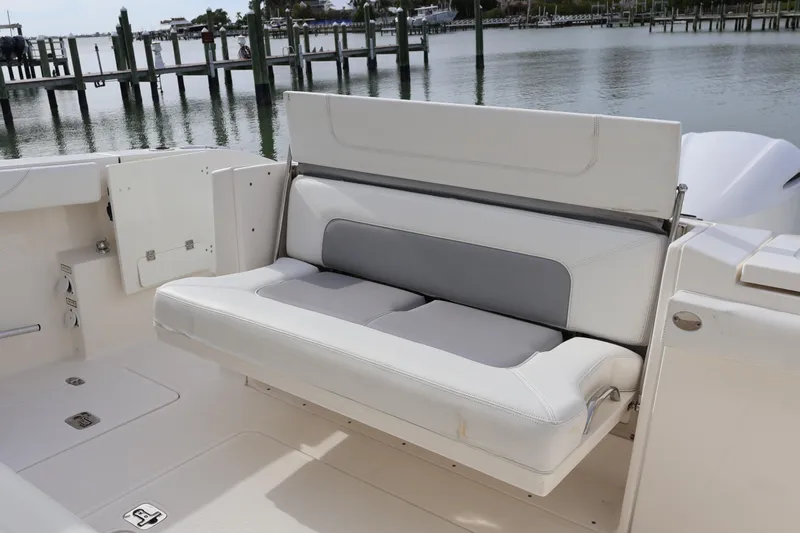 Yacht Photos Pics 2021 Pursuit S 328 Sport boat with foldable seating by the water.