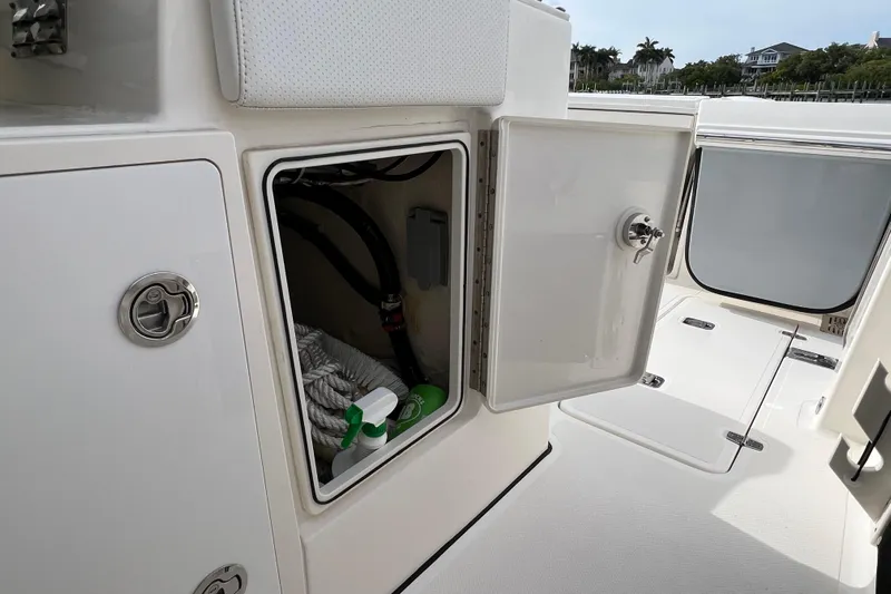  Yacht Photos Pics 2021 Pursuit S 328 Sport boat storage compartment with cleaning supplies and ropes.