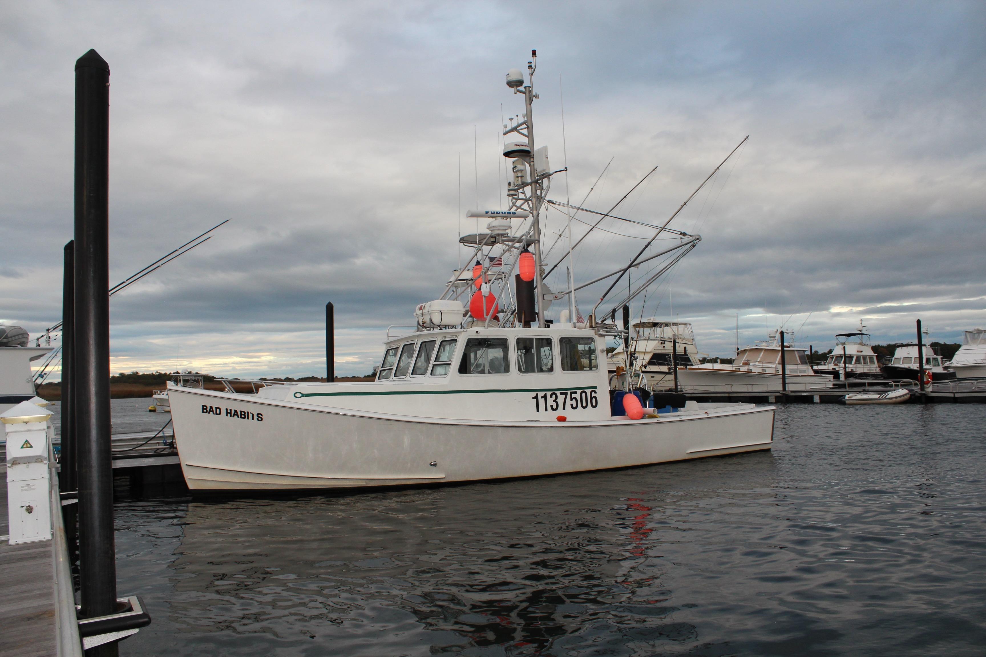 2002 Libby 38 Downeast boat docked at marina under cloudy sky.