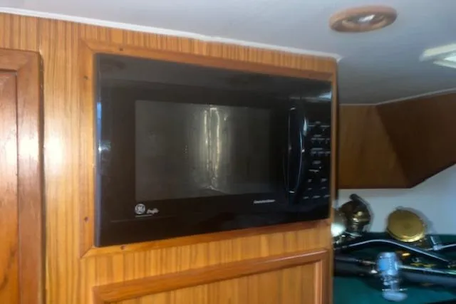 Bad Habits Yacht Photos Pics Built-in microwave in a 2002 Libby 38 Downeast boat interior with wood paneling.