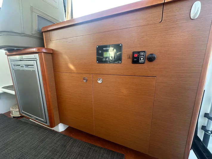 Marking Time Yacht Photos Pics Interior view of 2016 Jeanneau Merry Fisher 855, featuring wooden cabinetry and control panel.