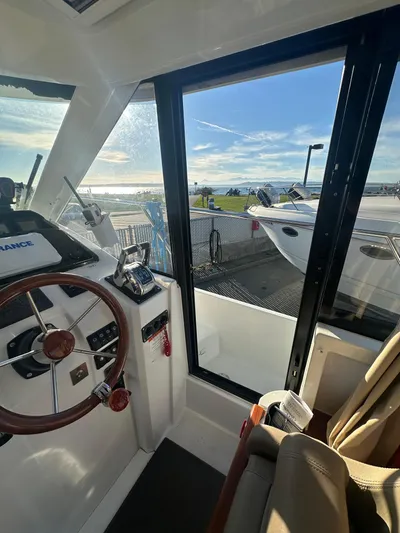 Marking Time Yacht Photos Pics Interior view of 2016 Jeanneau Merry Fisher 855 boat cockpit with steering wheel and controls.