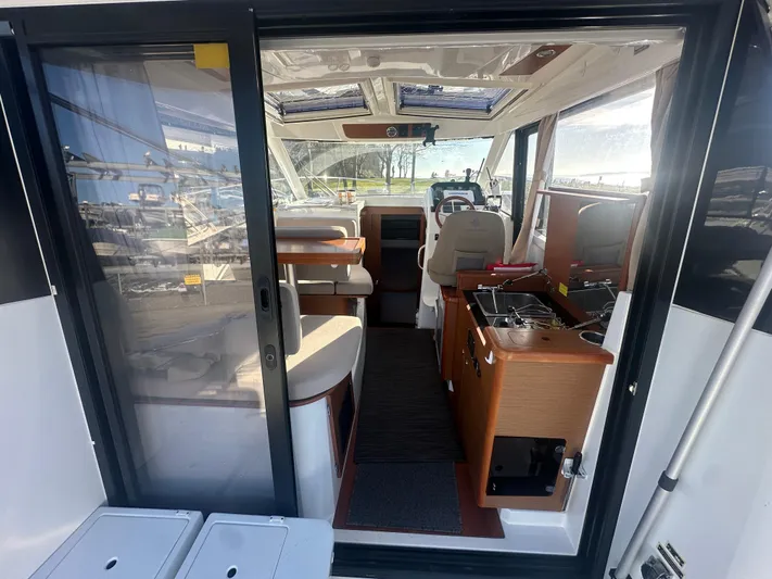 Marking Time Yacht Photos Pics 2016 Jeanneau Merry Fisher 855 interior with seating, helm, and kitchenette.