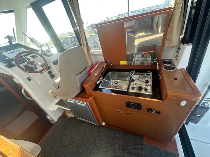 Marking Time Yacht Photos Pics Interior of 2016 Jeanneau Merry Fisher 855 with helm, stove, and seating area.