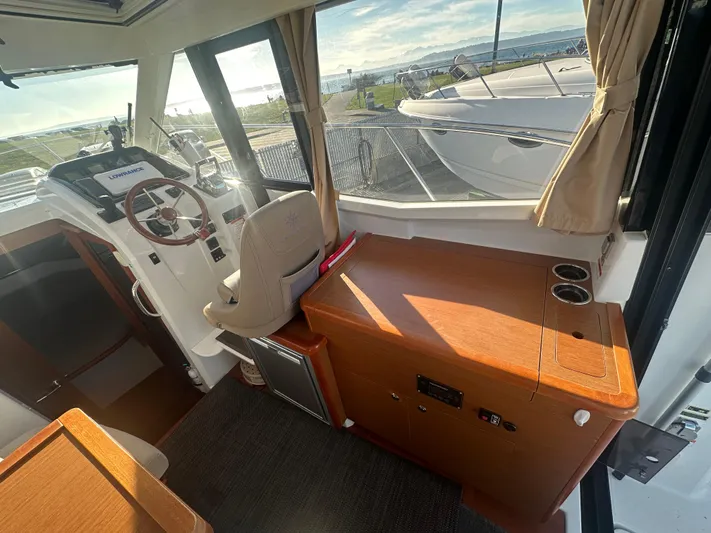 Marking Time Yacht Photos Pics Interior of 2016 Jeanneau Merry Fisher 855 boat with helm and wooden cabinetry.