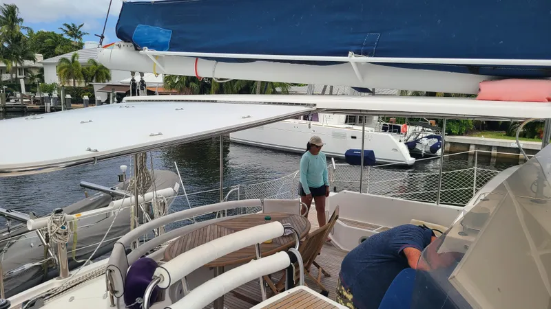 Pono Yacht Photos Pics 2005 Fountaine Pajot FP Eleuthera 60 catamaran docked, with people on deck, near waterfront homes.