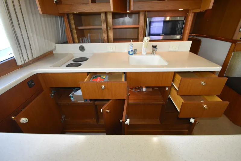 Whaler Yacht Photos Pics Kitchen area of a 1997 Ocean 48 Convertible yacht with open cabinets and drawers.