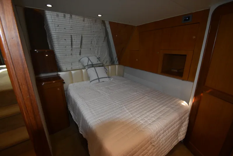 Whaler Yacht Photos Pics 1997 Ocean 48 Convertible yacht bedroom with white bedding and wooden cabinetry.