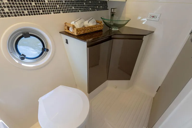 Music Yacht Photos Pics Modern bathroom in 2024 Hanover 415 yacht with porthole, glass sink, and mosaic tiles.