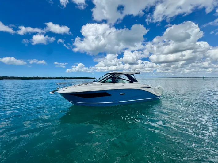  Yacht Photos Pics 2025 Sea Ray Sundancer 320 Outboard on calm water under blue sky.