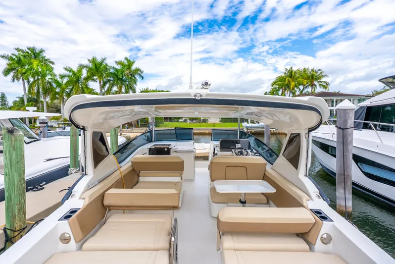 Ohana Yacht Photos Pics 2020 Aquila 32 yacht with spacious seating, docked near palm trees under a blue sky.