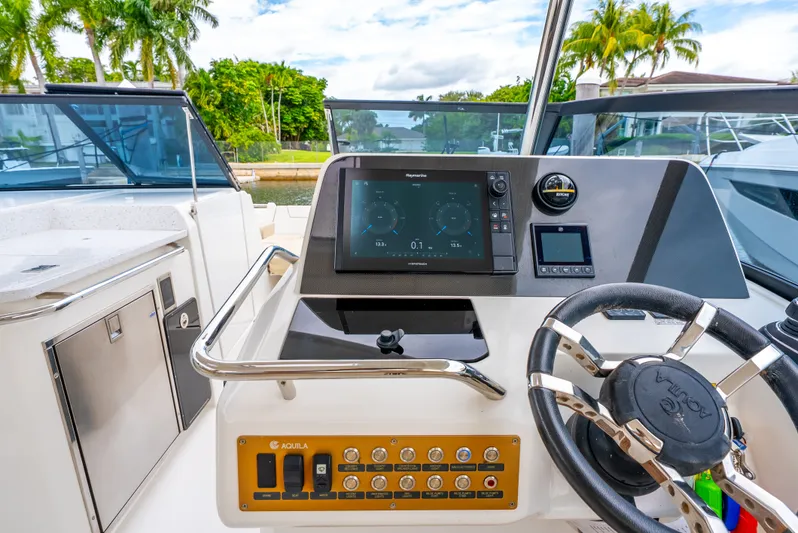 Ohana Yacht Photos Pics Aquila 32 boat helm with modern navigation system, 2020 model, docked near lush greenery.
