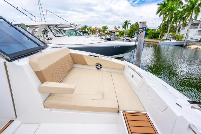 Ohana Yacht Photos Pics Aquila 32 boat interior with beige seating, docked near palm trees and other boats.