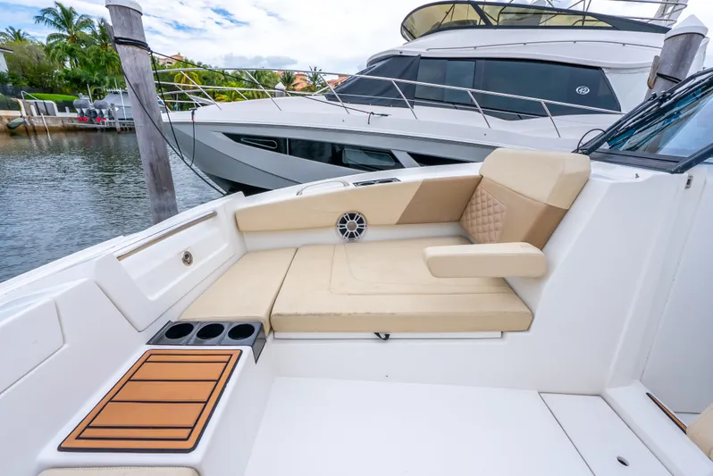 Ohana Yacht Photos Pics 2020 Aquila 32 boat interior with beige seating and cup holders, docked near another yacht.