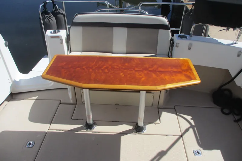 I'm Busy Yacht Photos Pics 2015 Cutwater 30 Command Bridge LE boat with wooden table and cushioned seating.