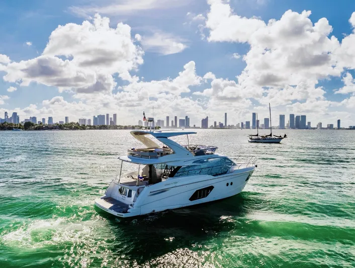 Sipsip Yacht Photos Pics Luxury yacht Absolute 52 FLY 2018 cruising on vibrant waters with city skyline backdrop.
