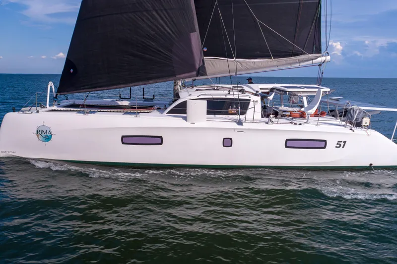 Rima Yacht Photos Pics 2018 Outremer 51 catamaran sailing on open sea with black sails.