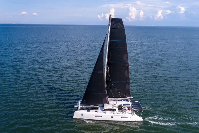 Rima Yacht Photos Pics 2018 Outremer 51 catamaran sailing on open sea with black sails.