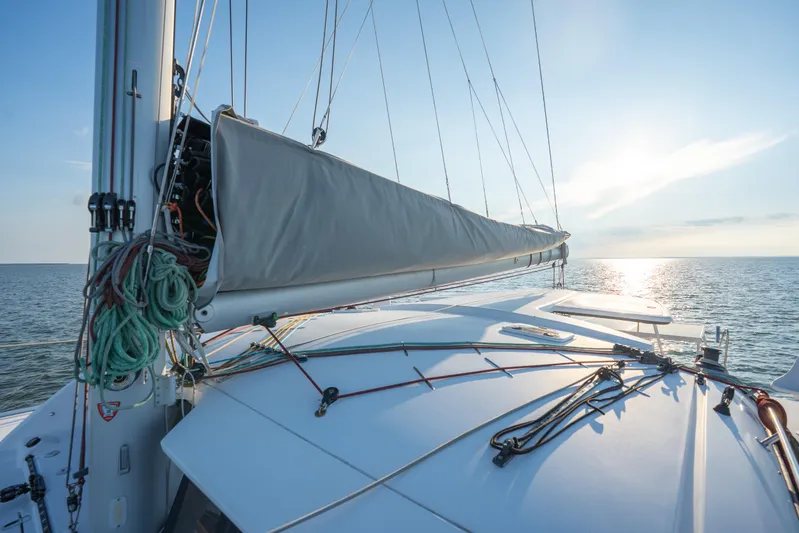 Rima Yacht Photos Pics 2018 Outremer 51 sailboat deck with rigging, sailing on calm sea at sunset.