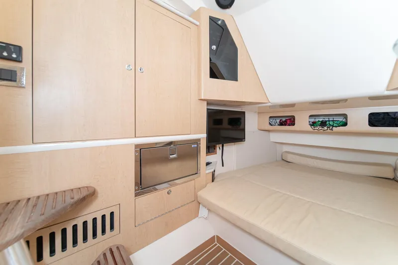 Vaquero Chingon Yacht Photos Pics 2016 Boston Whaler 370 Outrage cabin interior with beige furnishings and wooden cabinetry.