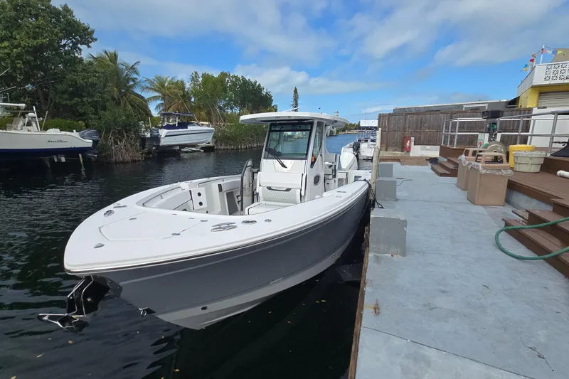  Yacht Photos Pics 2023 Blackfin 302 CC boat docked by a marina under a blue sky.