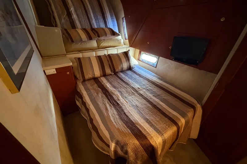 Fender Bender Yacht Photos Pics Cozy bedroom in 1996 Ocean Yachts 48 Super Sport with striped bedding and small window.