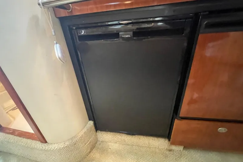 Irish Rover Yacht Photos Pics 2006 Sea Ray 360 Sundancer interior with compact black fridge and wooden cabinetry.