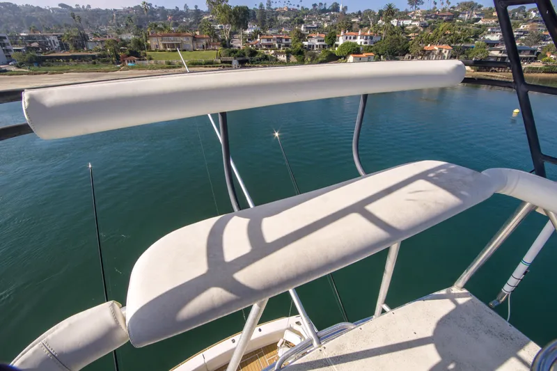 Aquila II Yacht Photos Pics 1990 Bertram 50 Convertible boat deck overlooking serene waterfront and residential area.