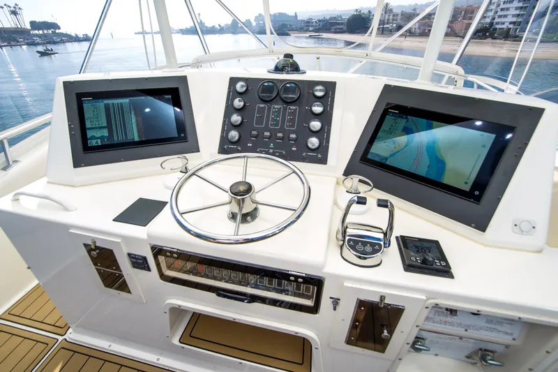 Aquila II Yacht Photos Pics Control panel of a 1990 Bertram 50 Convertible yacht with navigation screens and steering wheel.